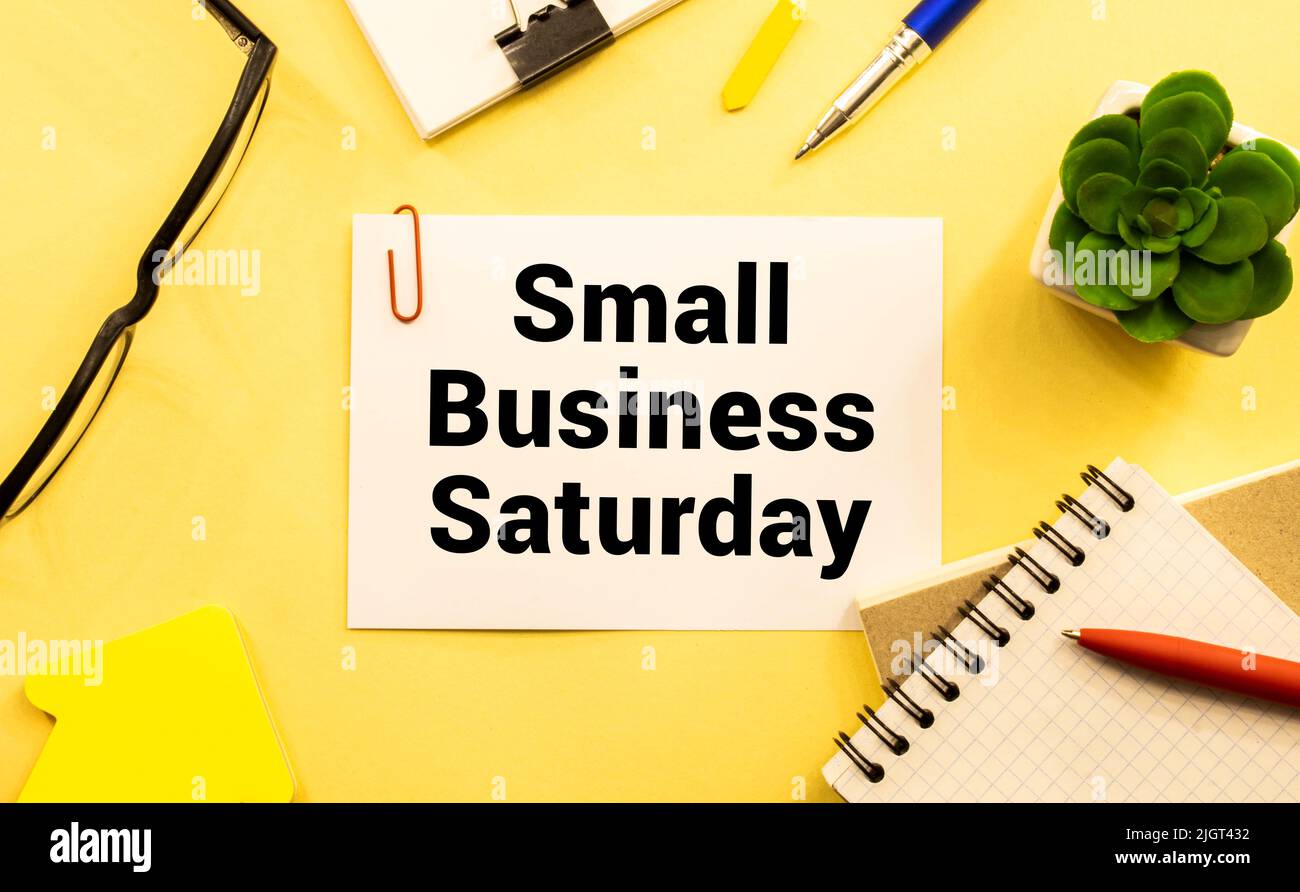 Text Small Business Saturday in Notebook auf weißem Tisch mit Office-Tools Stockfoto