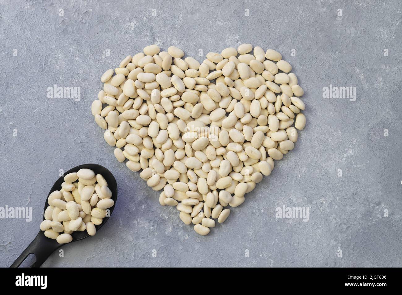 Weiße Kidney-Bohnen in Herzform auf weißem Hintergrund.Draufsicht. Stockfoto