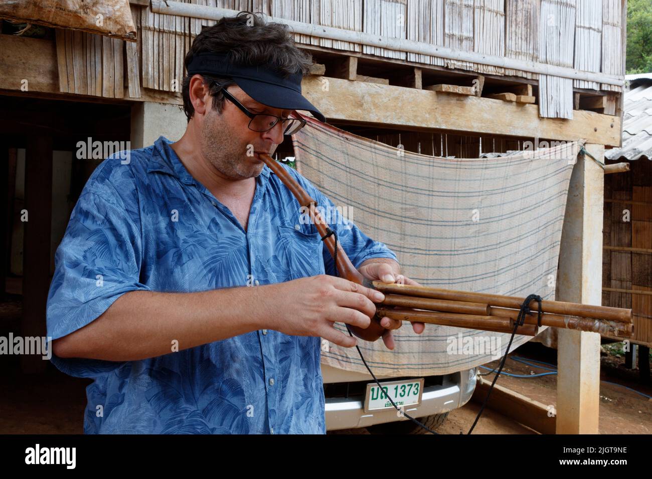 Bodhi Garrett plant ein lokales Instrument in einem DORF IN LIHU entlang des MAE KOK Flusses von Thaton nach Chiang Rai - THAILAND Stockfoto