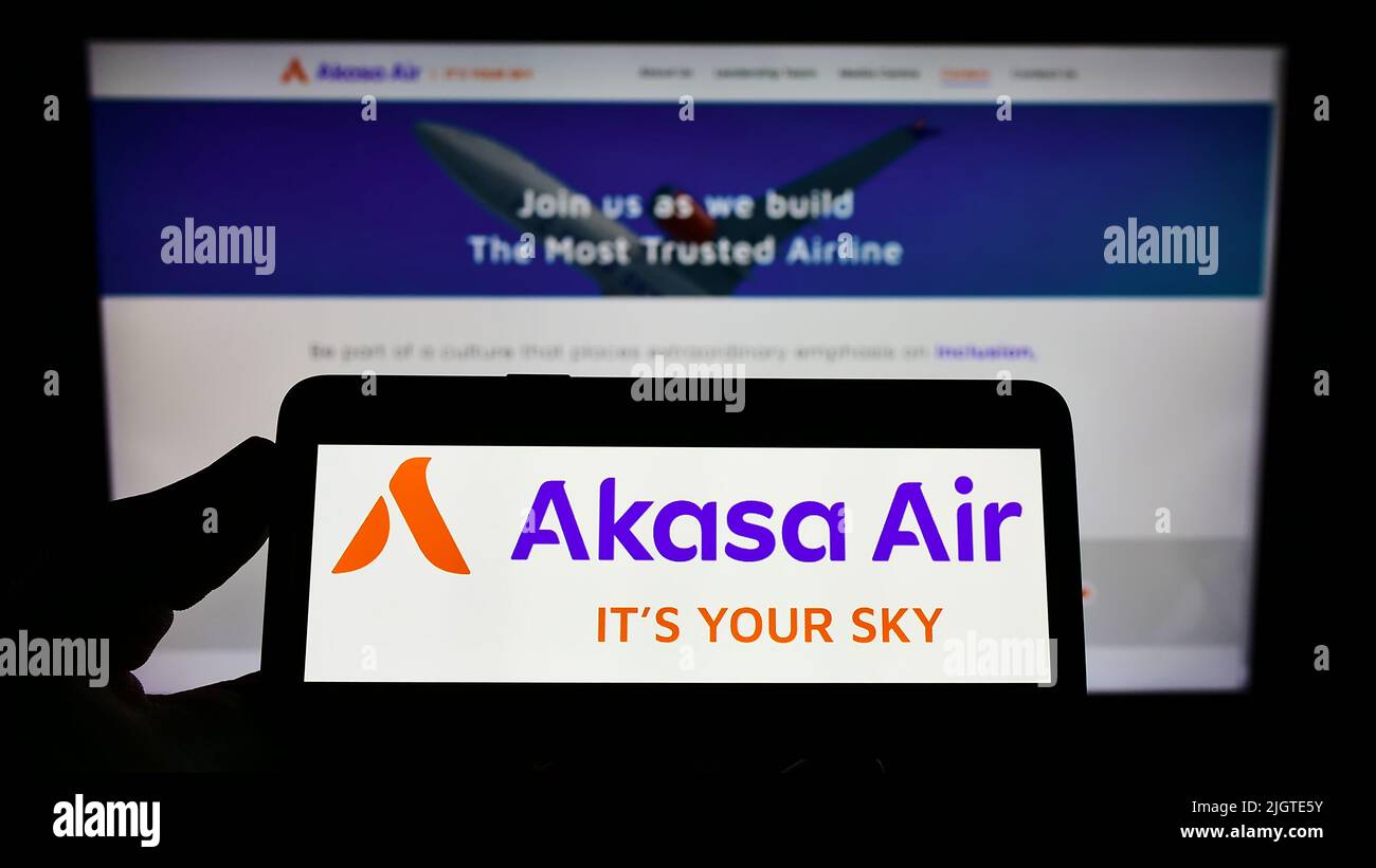 Person, die das Smartphone mit dem Logo der Fluggesellschaft SNV Aviation Private Limited (Akasa Air) auf dem Bildschirm vor der Website hält. Konzentrieren Sie sich auf die Telefonanzeige. Stockfoto