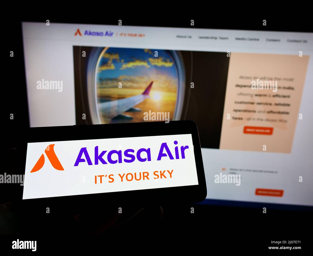 Person mit Mobiltelefon und Logo der Fluggesellschaft SNV Aviation Private Limited (Akasa Air) auf dem Bildschirm vor der Webseite. Konzentrieren Sie sich auf die Telefonanzeige. Stockfoto