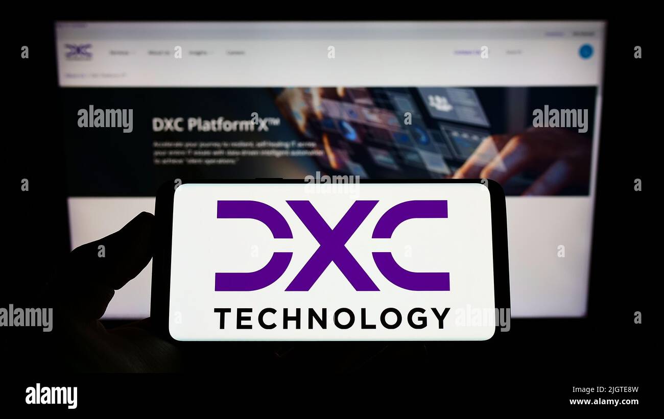 Person, die das Smartphone mit dem Logo des US-AMERIKANISCHEN IT-Beratungsunternehmens DXC Technology Company auf dem Bildschirm vor der Website hält. Konzentrieren Sie sich auf die Telefonanzeige. Stockfoto