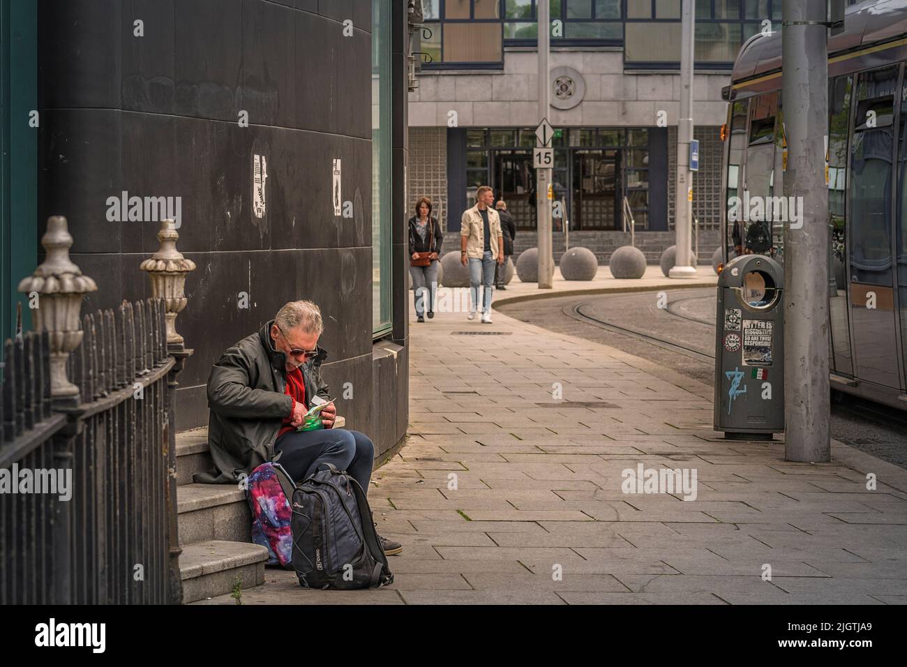 Ein älterer Mann rollt eine Zigarette auf der Seite eines Gebäudes. Dublin. Irland. Stockfoto