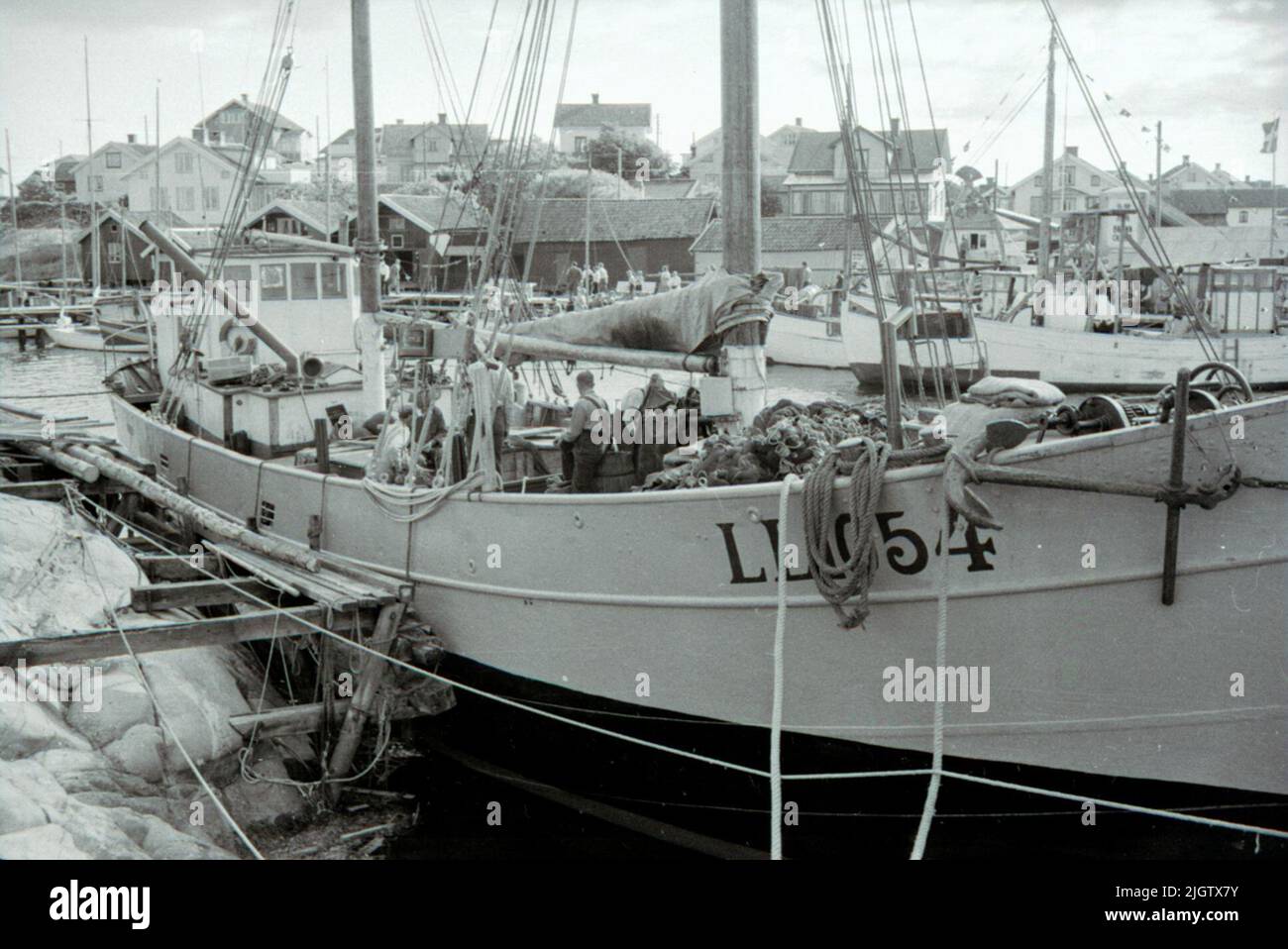 Vorbereitungen für den isländischen Fischfang an Bord LL 1054 Knape, Hafen Käringö "Vorbereitung für den isländischen Fisch. Das Garn wird in Ordnung hergestellt. Das Boot ist vor dem isländischen Angeln fertig. Das Garn wird überprüft, und das große Garnkabel wird an Bord genommen. Auf dem Deck ist Carl -Birger Karlsson in voller Aktivität. Das Boot gehörte August Berlin (1890 - 1961) und Carl -Birger Karlsson (1892 - 1960) in Partkrederi.ll 1054 Knape, Reg. Nr. 7667, im isländischen Fischfang waren die Sommer 1949 - 1954. Im Winter gab das Boot auf die Schifffahrt mit Fracht zwischen Schweden - Deutschland, manchmal England, Finnland. Stockfoto
