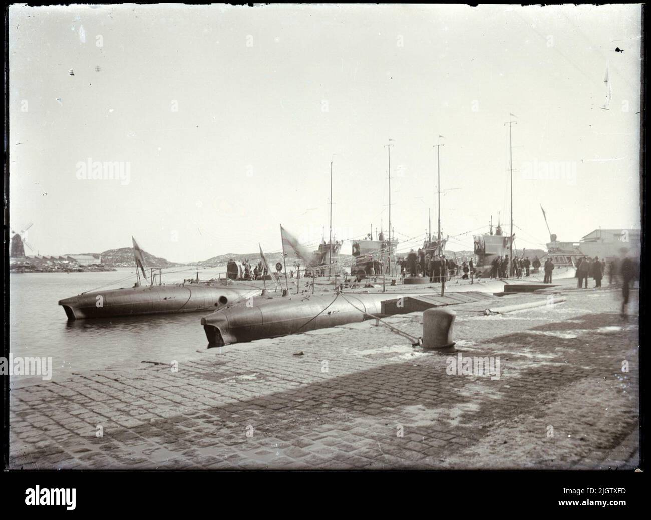 U-Boote am Kai, ('Tråmen' - die Unterbringungsschiffe des Shipbuilding Board - innen). Einige Neugierige haben sich am Kai versammelt. Stockfoto