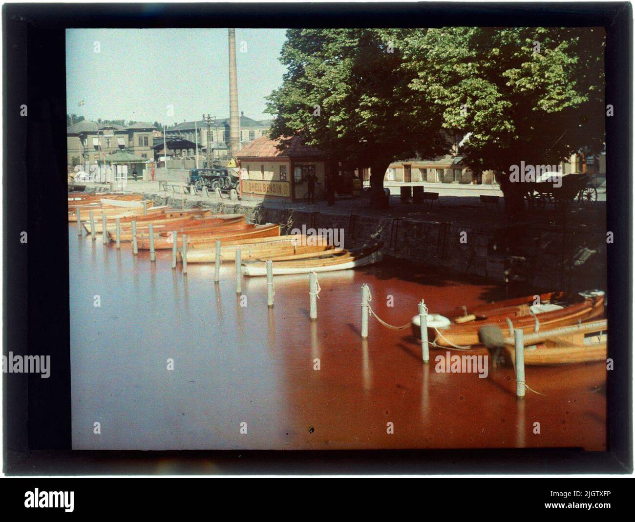 Bäveån und Uddevalla Tropstation 1928 Bäveån mit Uddevalla Tropstation im nördlichen Kajen Uddevalla. Hier wurden Autos und Pferderassen um dasselbe Bahnhofsgebäude versammelt. Beachten Sie das Schild mit dem Text Shell Benzin. Die erste Autohose hatte bereits 1911 begonnen, die Uddevallas zu passieren. Im Hintergrund sind das Fabrikgebäude des Kampenhofs und der Hafenbahnhof zu sehen. Ein gut gemachtes Holzkratz, auf dessen Deckel GWCQT Uddevalla im Jahr 1928 geschnitten wurde. Die Kiste wurde im Stadtarchitekturarchiv Uddevalla gefunden und 1982 dem Museum von Bohuslän gespendet. Wie die Glasplatten am Stadtbogen gelandet sind Stockfoto