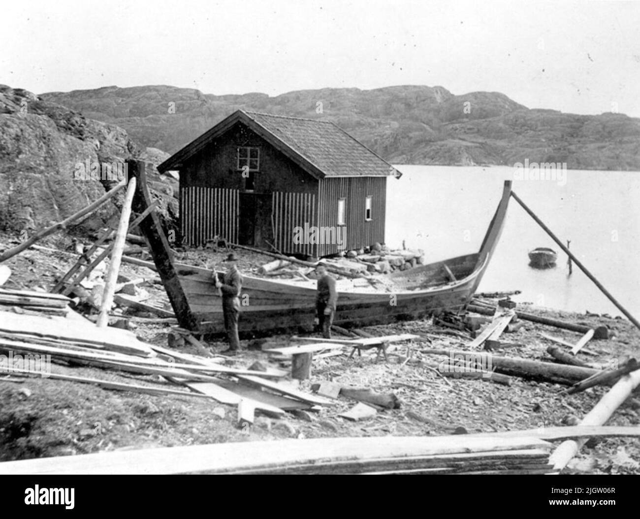 Tischfüllung, Vasseröd, Bohuslän 1902. Auf der Rückseite: Kachelboot während der Tischfüllung. Vasseröd, Bohuslän.fotografiert von: G.B.G. Museum. Der Bau eines Klinkergebäudes begann mit dem Auslegen und die Öfen wurden errichtet. Einige Vorlagen wurden nicht verwendet. Die Form wurde vollständig durch die Art und Weise gesteuert, wie die Tische und Außenseiten an den Rändern phasiert wurden. Hier war echte Handwerkskunst gefragt. Es wurden Boote mit einer Tragfähigkeit von bis zu 100 Tonnen gebaut. Als der Rumpf komplett mit Tisch gefüllt war, wurden die Verstärkungen - Bodenschächte, Anordnungen eines Zauns und Balkenwege hinzugefügt. Stockfoto