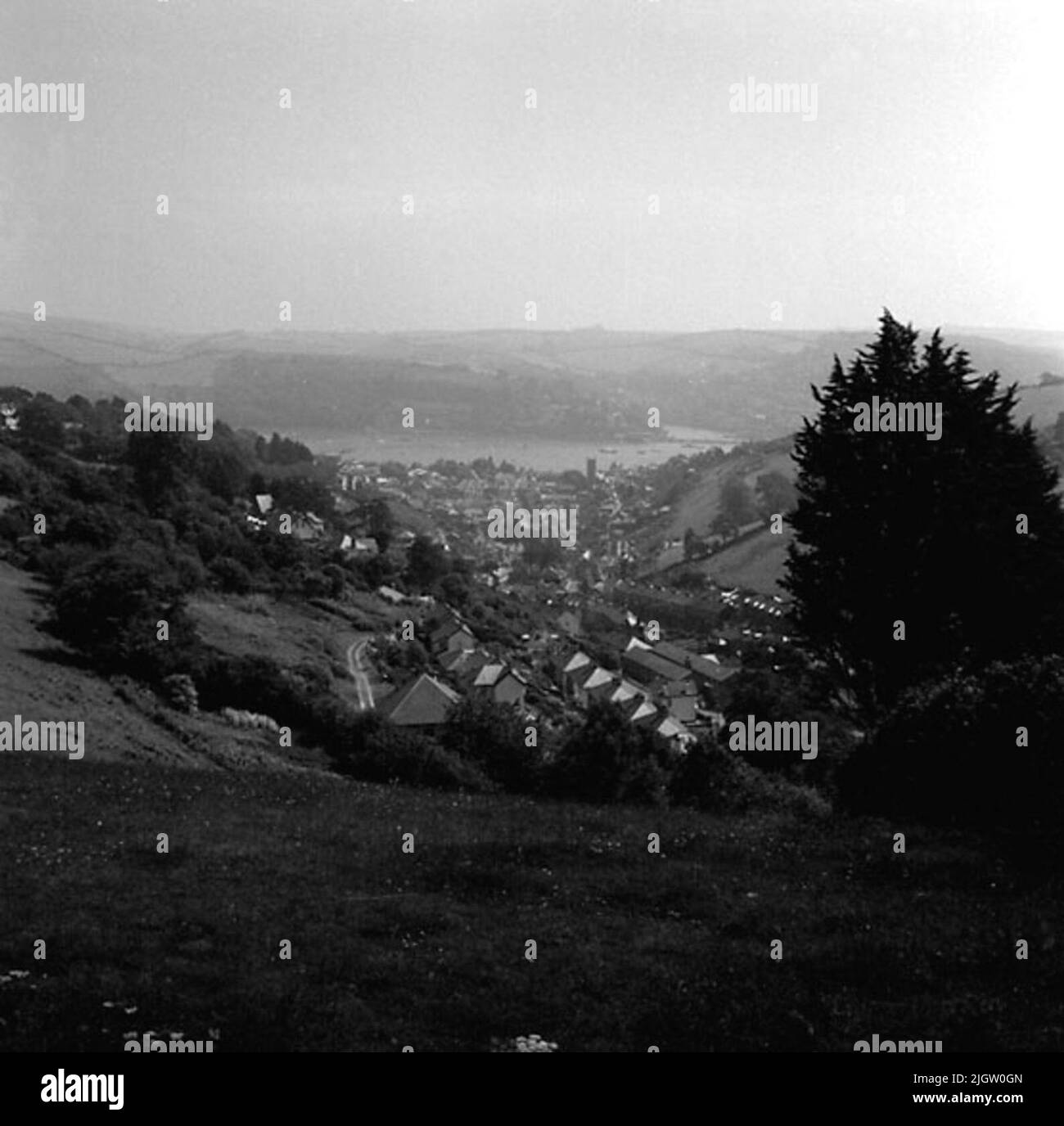 Zwischen zwei Bergen liegt eine Gemeinde. Im Tal liegt eine Meeresbucht (?). Im Vordergrund der Gesellschaft sind eine Reihe von Wohngebäuden zu sehen. Stockfoto