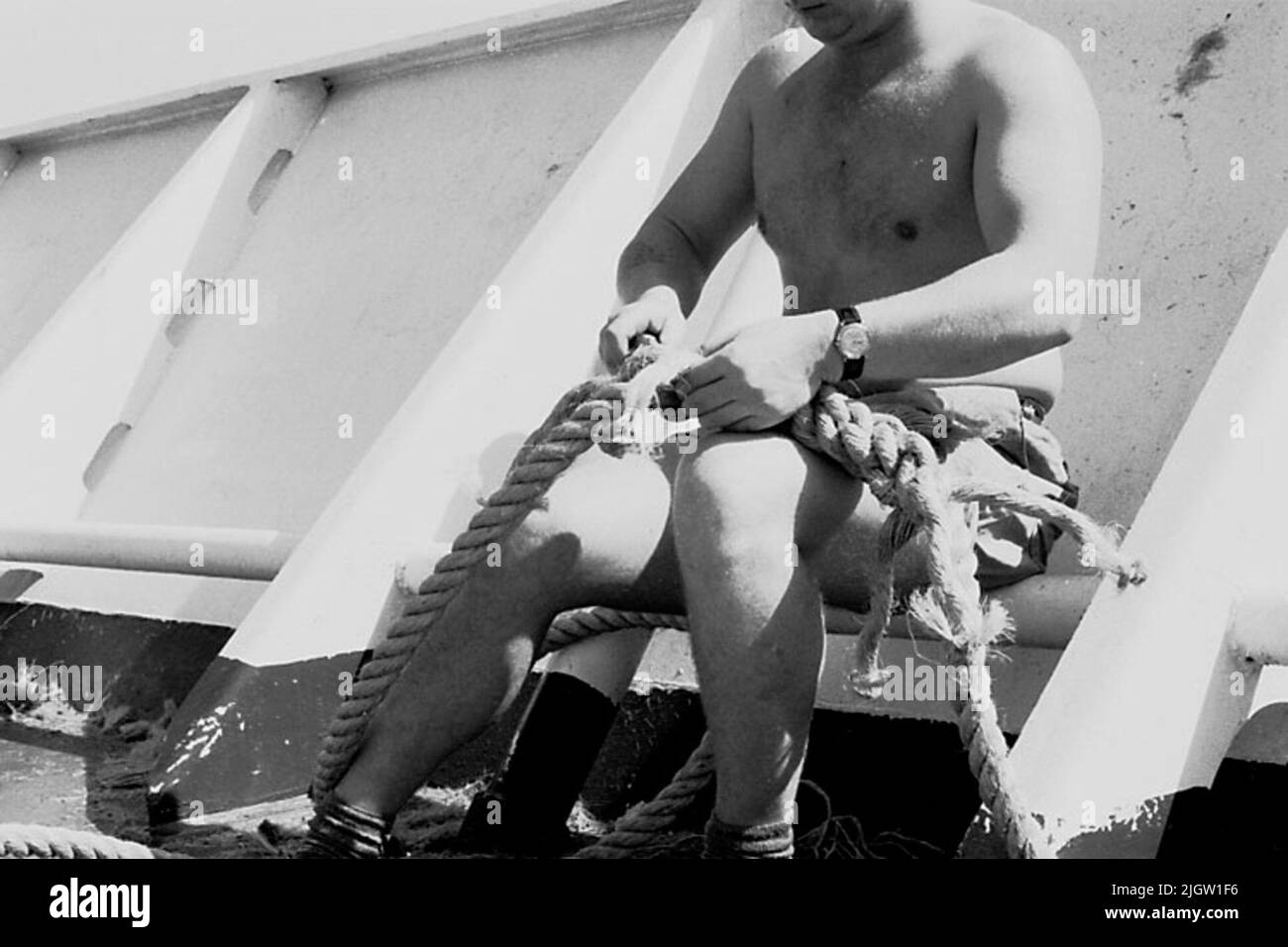 Das Foto wurde ungefähr 1961-09-22 aufgenommen. Ein Mann sitzt auf einem Schiff. Er teilt das Zugholz zusammen. African travel35 Bilder in Serie. Stockfoto