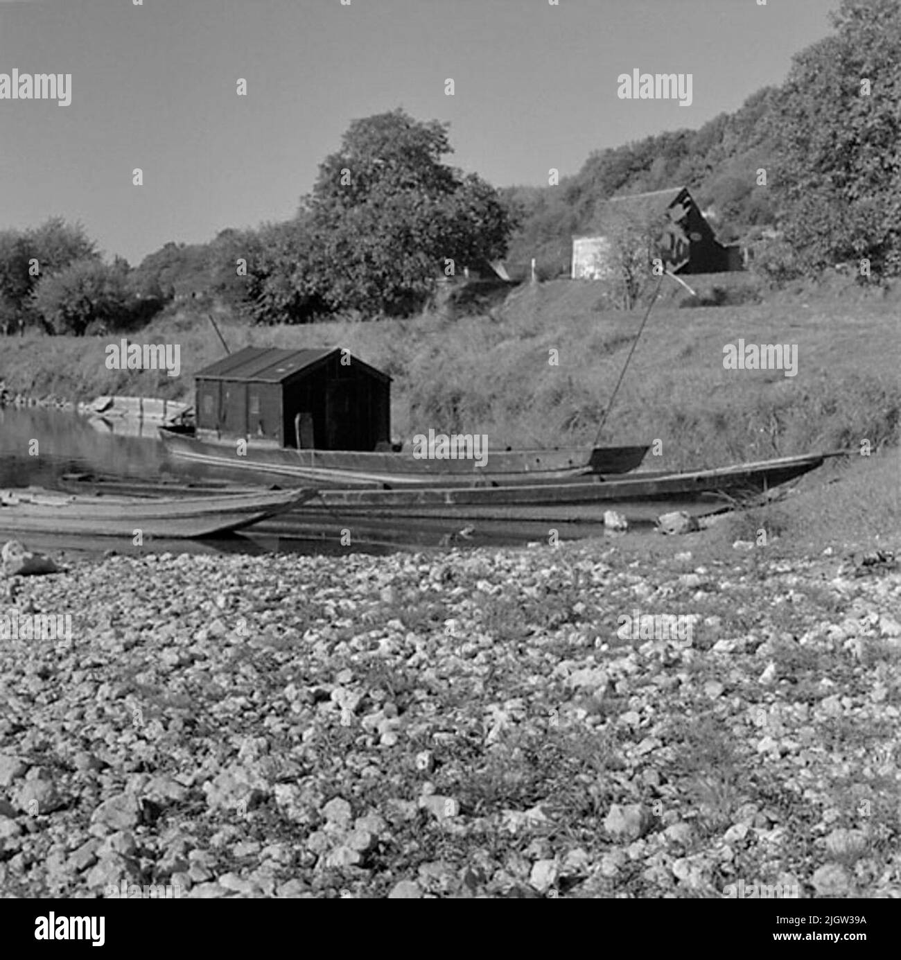 5. Frankreich. Fotojournal ist bei B.M.A. erhältlich + Fotoalben. Erwerb: Bücher und Archivmaterial. Fotos aufgenommen 1959-10-16,12 Bilder in Serie. Nach Angaben: Frankreich. Loire, St Etienne de Chigny, 16/10 -59. Flachbodenboot des üblichen Typs mit Karosserie. Drei Boote befinden sich an einem Strand zu einem Fluss. Eines der Boote hat einen Überbau. Im Hintergrund ist ein weiteres Boot teilweise unter Wasser am Strand zu sehen. Am Strand hinter dem Boot sitzt ein Mann und traf sich. Auf der rechten Seite befindet sich ein Wohngebäude etwas weiter oben am Strand. Stockfoto