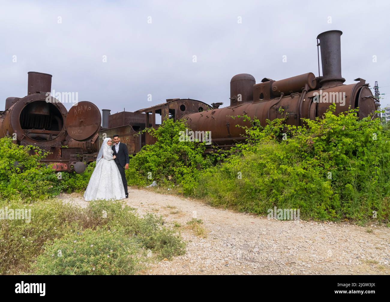 Frisch verheiratetes Paar vor der Alten Lokomotive der Beirut-Damaskus-Linie, North Governorate, Tripoli, Libanon Stockfoto