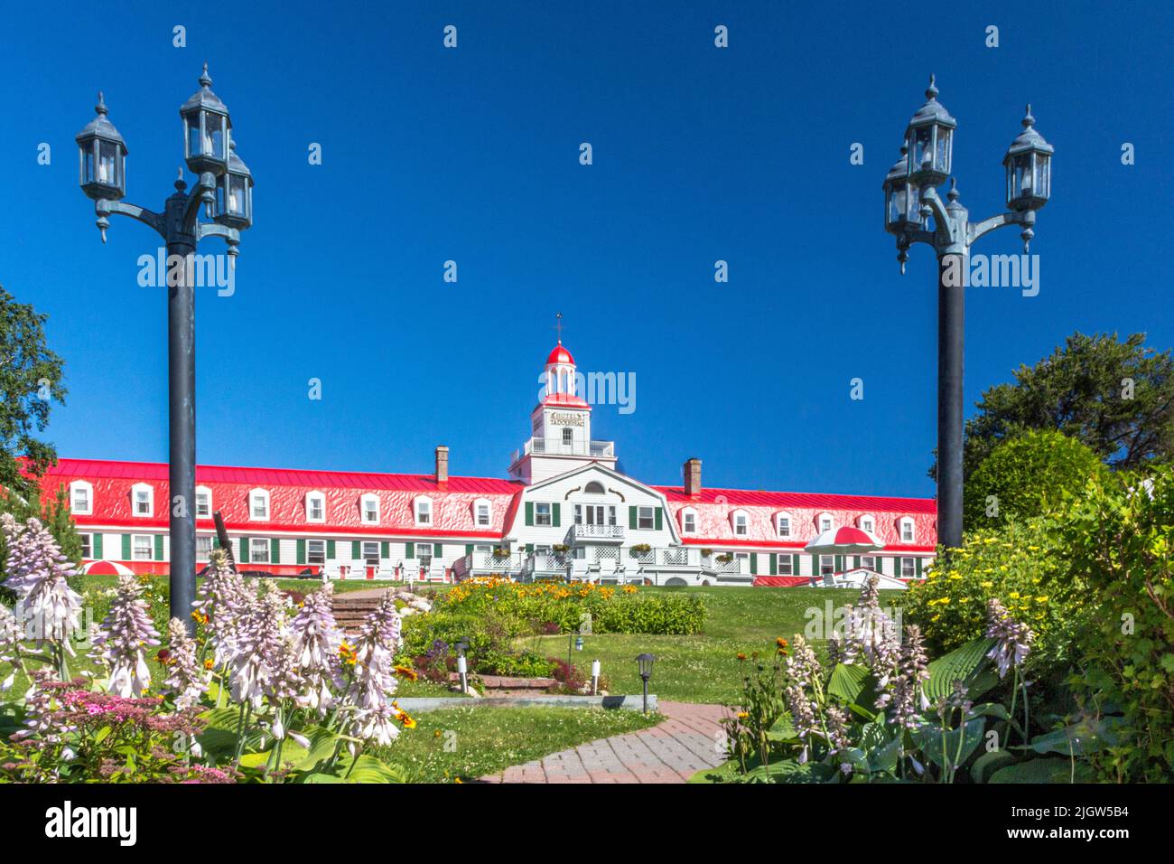 Vorderansicht des Hotels Tadoussac, Tadoussac, Quebec, Kanada mit Straßenlampen und einem Weg zum Hotel. Stockfoto