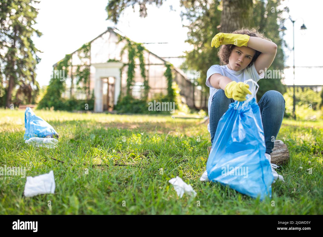 Nette junge Freiwillige, die müde nach dem Sammeln von Müll aussehen Stockfoto