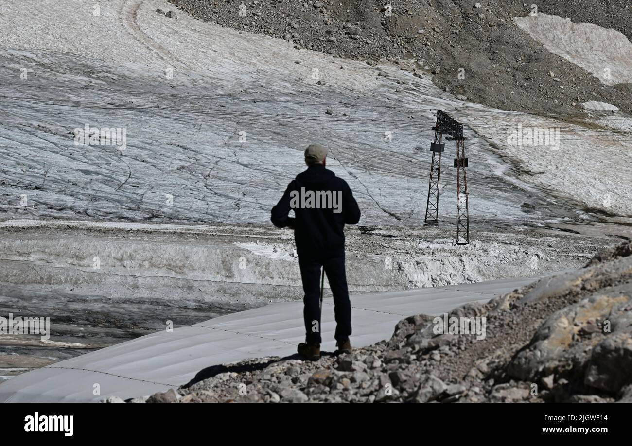 Grainau, Deutschland. 13.. Juli 2022. Ein Wanderer schaut auf die Überreste des nördlichen Schneefernergletschers auf dem Zugspitzplatt. Die warmen Temperaturen beeinflussten in diesem Sommer die Reste des Gletschers auf der Zugspitze. Quelle: Angelika Warmuth/dpa/Alamy Live News Stockfoto