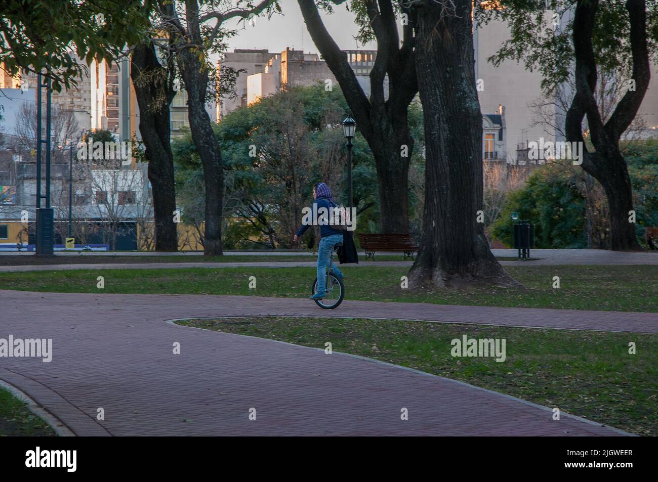 Ein junger Mann, der im Parque Lezama im Bezirk San Telmo, Buenos Aires, Argentinien, ein Einrad reitet Stockfoto