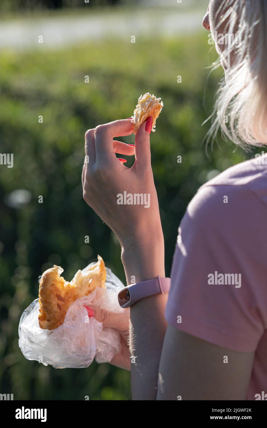 Frau bricht im Park ein Stück Brötchen ab. Hochwertige Fotos Stockfoto