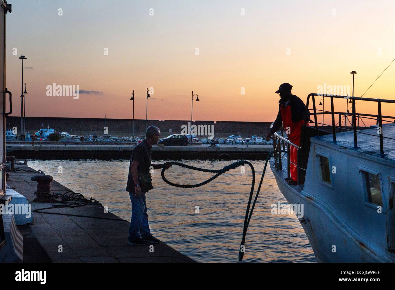 Europa, Italien, Sardinien, Porto Torres, Fischer legen im Morgengrauen am Hafen an. Stockfoto