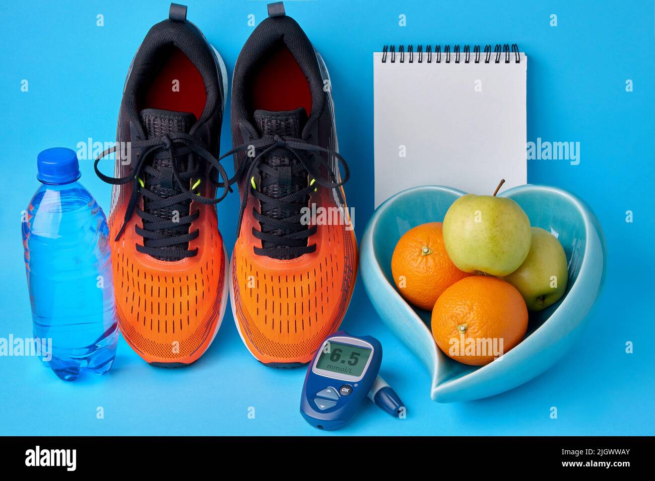 Orangefarbene Turnschuhe, ein Notizbuch-Tagebuch, ein Glucometer, eine Flasche Trinkwasser und Früchte. Konzept eines gesunden Lebensstils zur Aufrechterhaltung normaler Blutglucos Stockfoto