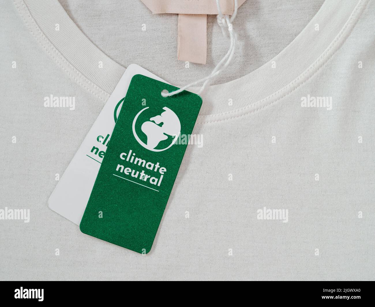 Carbon-neutrales T-Shirt, Label Climate neutral auf neuer Kleidung. CO2-neutrales Label-Konzept in der Bekleidungs- und Modeindustrie. Ethischer Konsum.Sensibilisierung für Kunden - Carbon footpint Stockfoto