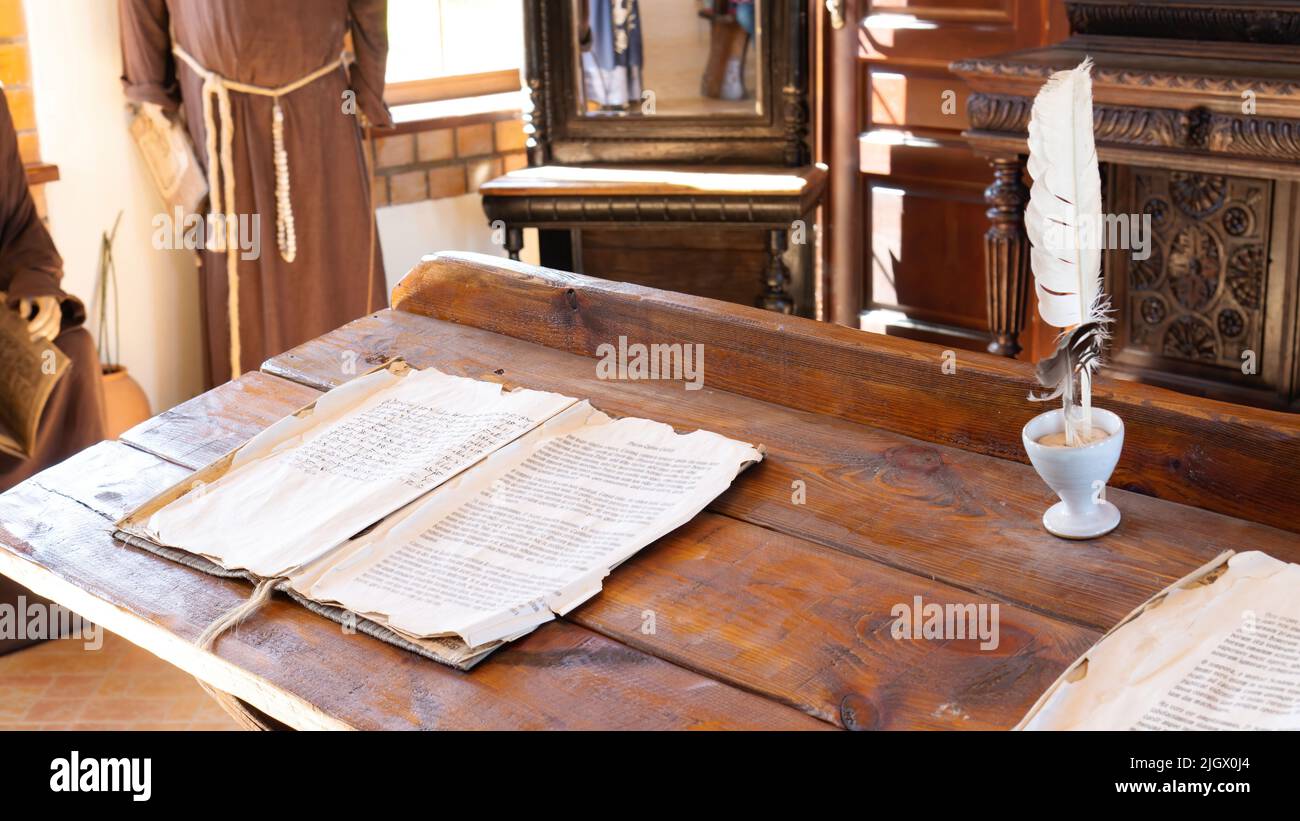 Schulklasse in alten Zeiten. Ein altes Manuskript auf einem hölzernen Schreibtisch, das im Mittelalter in einem katholischen Kloster Lesen und Schreiben lehrte. Schreiben Stockfoto