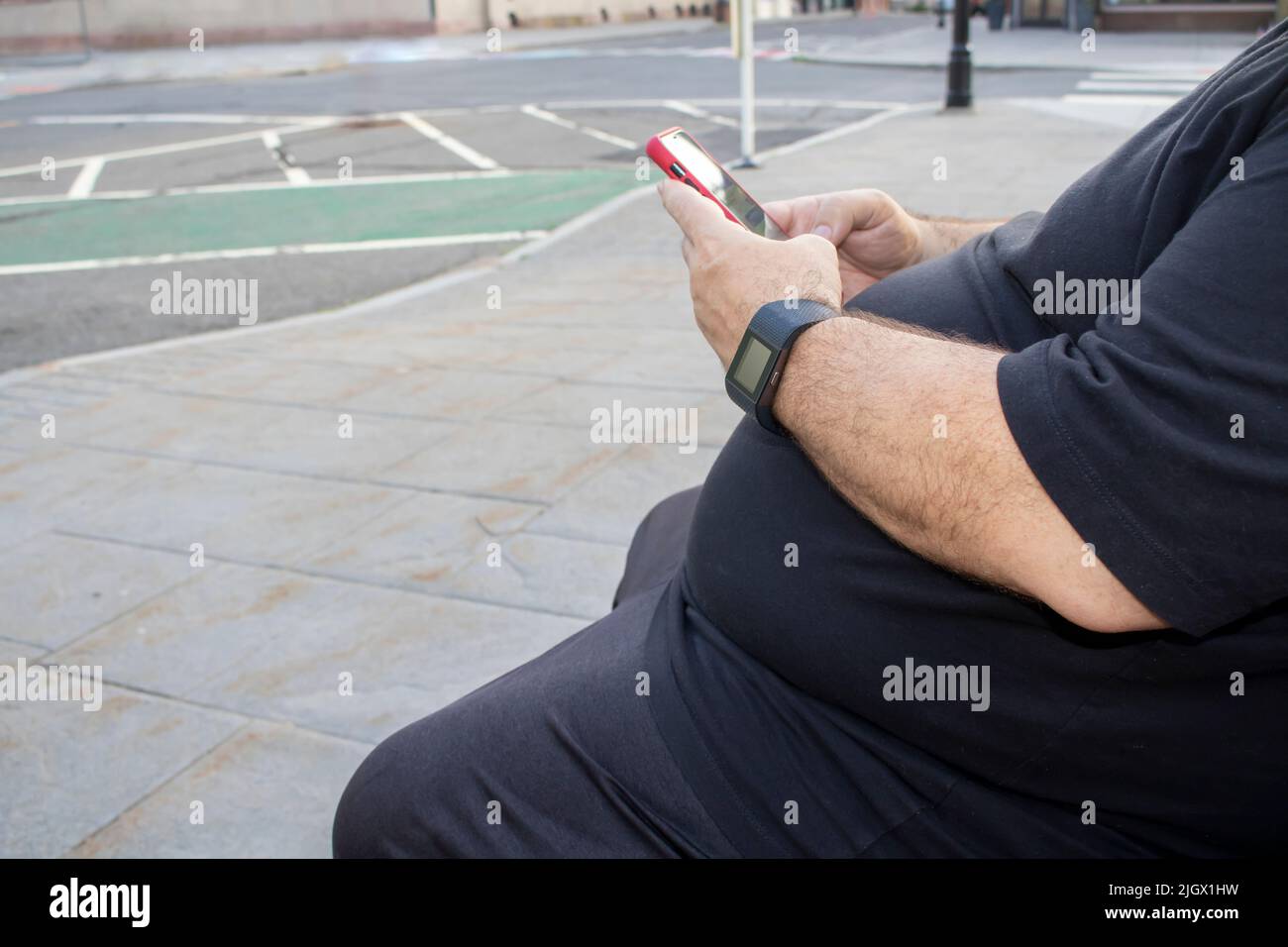 Bauchfett Bauchfettleibigkeit ist das deutlichste Zeichen für Typ-2-Diabetes-Risiko Mann sitzt mit einem Handy Stockfoto