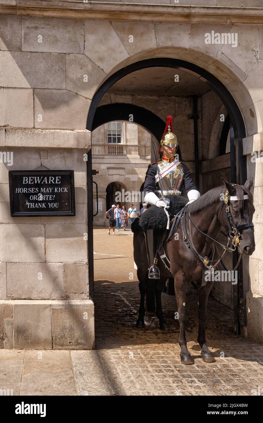 Auf einem Pferd montiert, ein Mitglied der Household Cavalry, auf der Wache in Whitehall, London, Warnt Ein Schild, dass das Pferd beißen könnte. Stockfoto