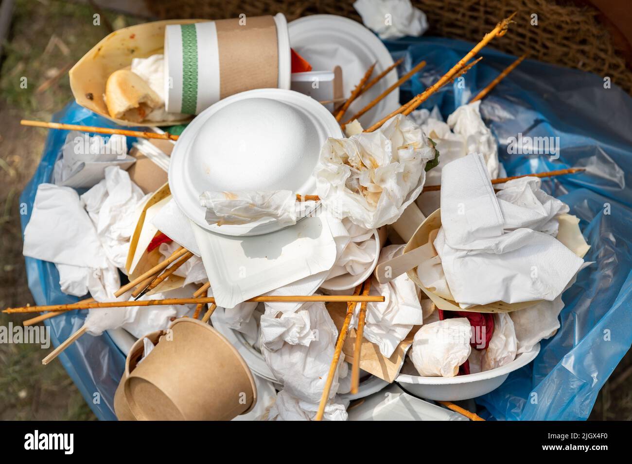 Nahaufnahme der vollen Mülltonne mit gebrauchten schmutzigen Papierkartons basteln wiederverwendbare nachhaltige Becher, Teller, Handtuchservietten und Besteck im Freien Stockfoto