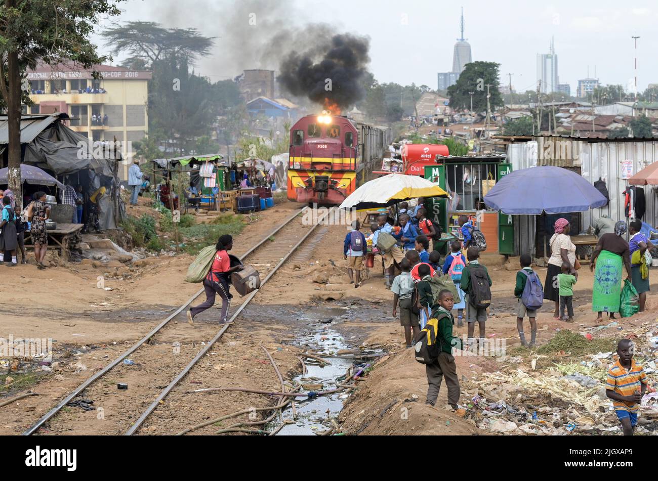 KENIA, Nairobi, Kibera Slum, Eisenbahnlinie, Güterzug, Hinter dem Wolkenkratzer im Stadtzentrum / KENIA, Nairobi, Kibera Slum, Bahnlinie, Güterzug Stockfoto