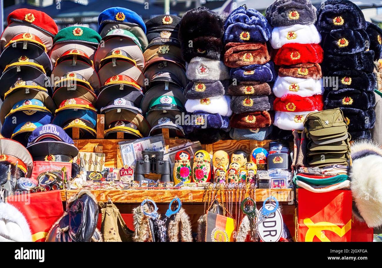Berlin, 21. Juni 2022: Mützen, Hüte und Souvenirs mit den Insignien der Sowjetunion und der Deutschen Demokratischen Republik an einem Stand in der Nähe von CHEC Stockfoto