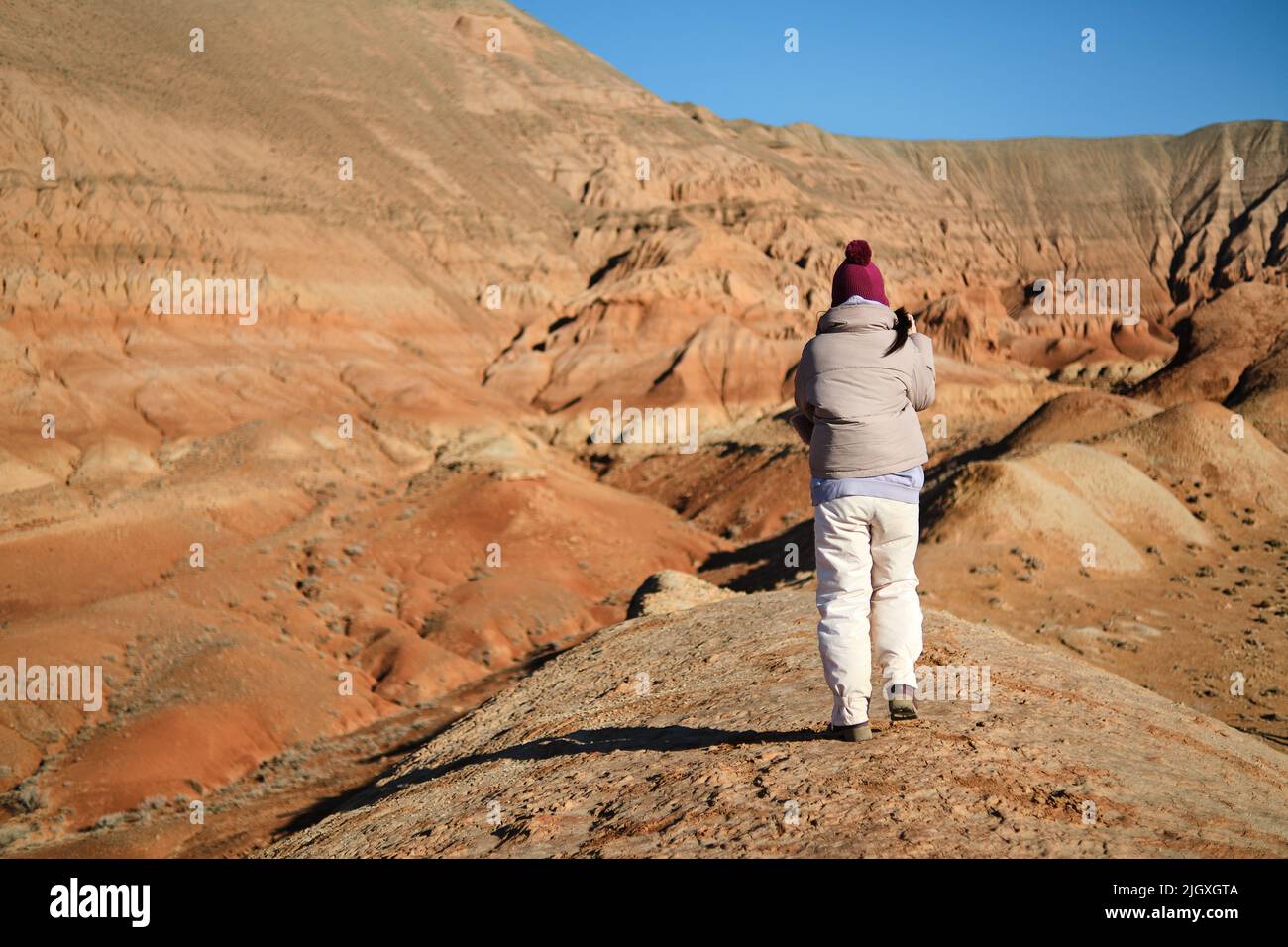 Asiatische Frau zu Fuß in der hügeligen Gegend der roten Berge von Boguty Stockfoto