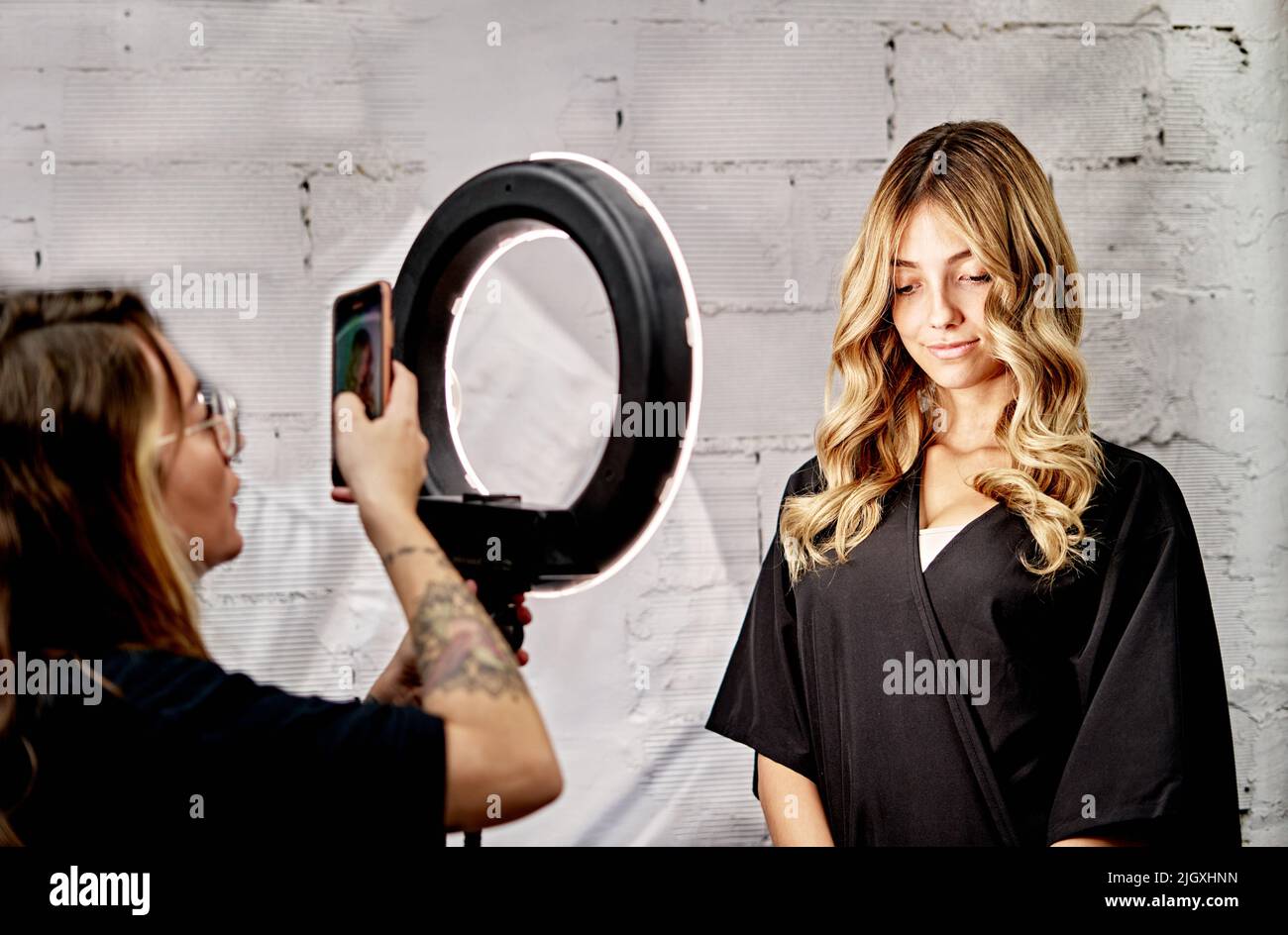 Friseurin erfasst ein Bild ihres Kunden mit dem Mobiltelefon Stockfoto
