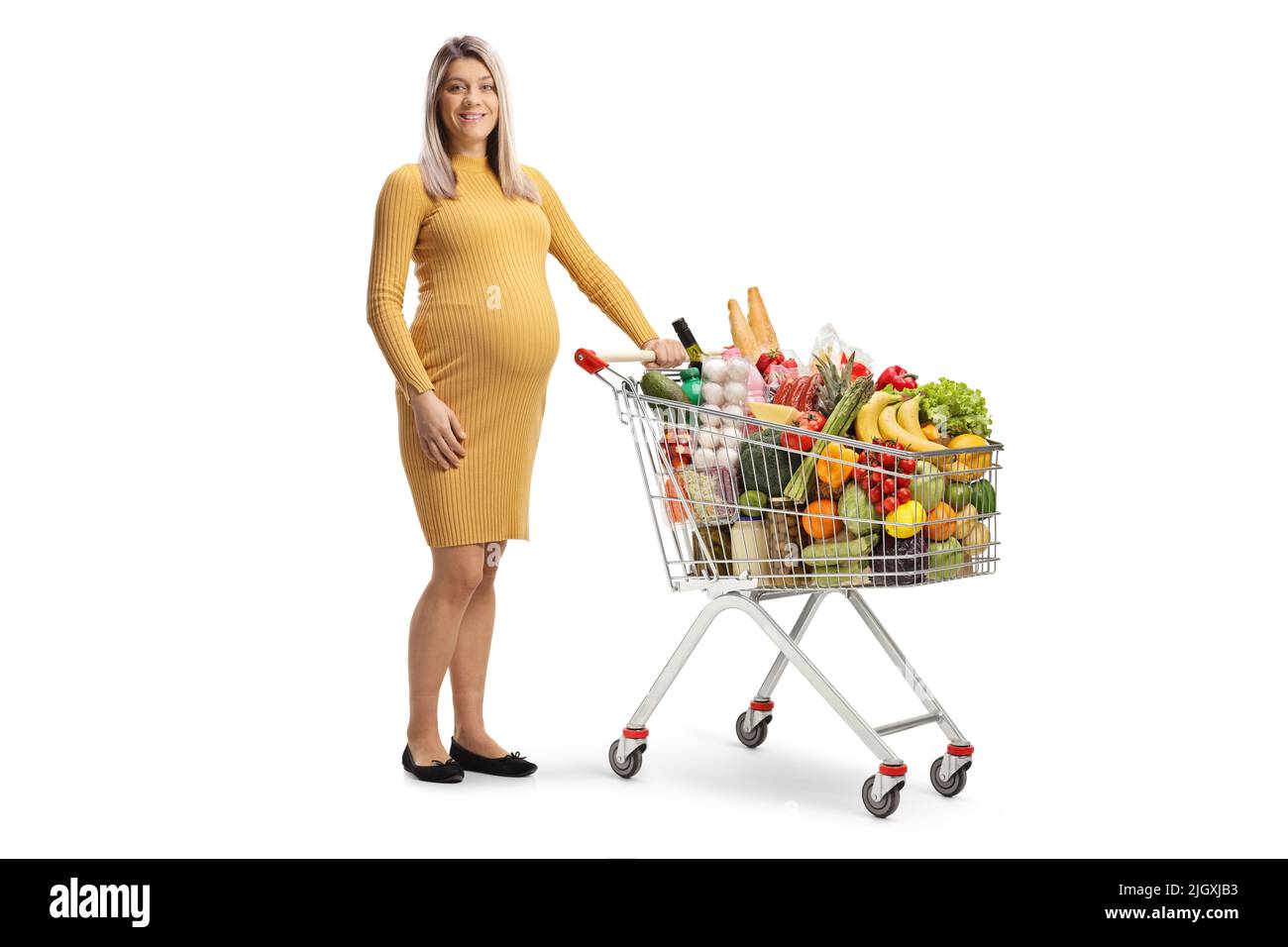 Schwangerin steht mit einem Einkaufswagen voller Lebensmittel isoliert auf weißem Hintergrund Stockfoto