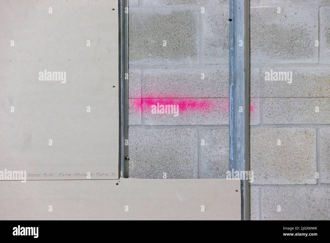 Trockenbauplatten, teilweise auf verzinkten Stahlrahmenstreben in einem Geschäftsgebäude installiert, das auf einer Wand aus Zunder-/Betonblöcken aufgestellt ist. Stockfoto