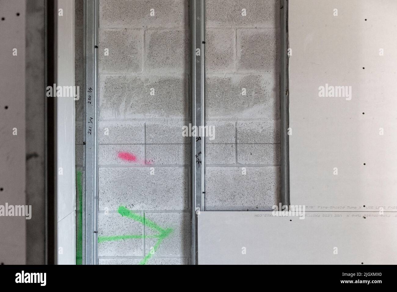 Trockenbauplatten, teilweise auf verzinkten Stahlrahmenstreben in einem Geschäftsgebäude installiert, das auf einer Wand aus Zunder-/Betonblöcken aufgestellt ist. Stockfoto