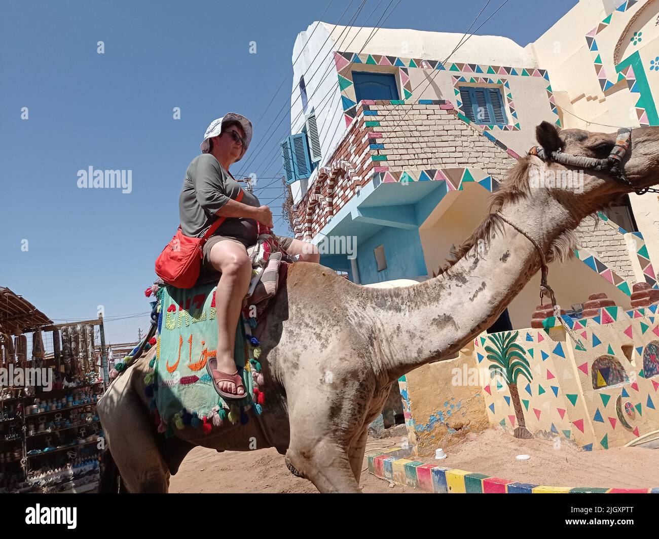 Touristen mittleren Alters reiten auf einem Kamel auf einem nubischen Dorf in Ägypten, Afrika Stockfoto