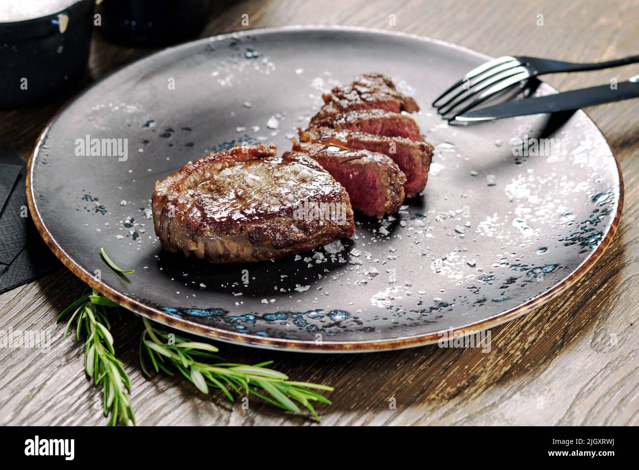 Nahaufnahme geschnittenes mittelseltenes Steak, serviert auf Teller mit Besteck. Hauptgericht, Restaurantgericht, Esskonzept Stockfoto