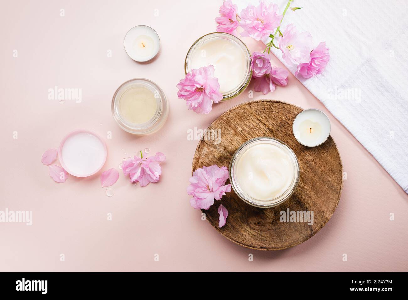 Körperpflegecreme und rosa Kirschblüten. Flach liegend. Stockfoto