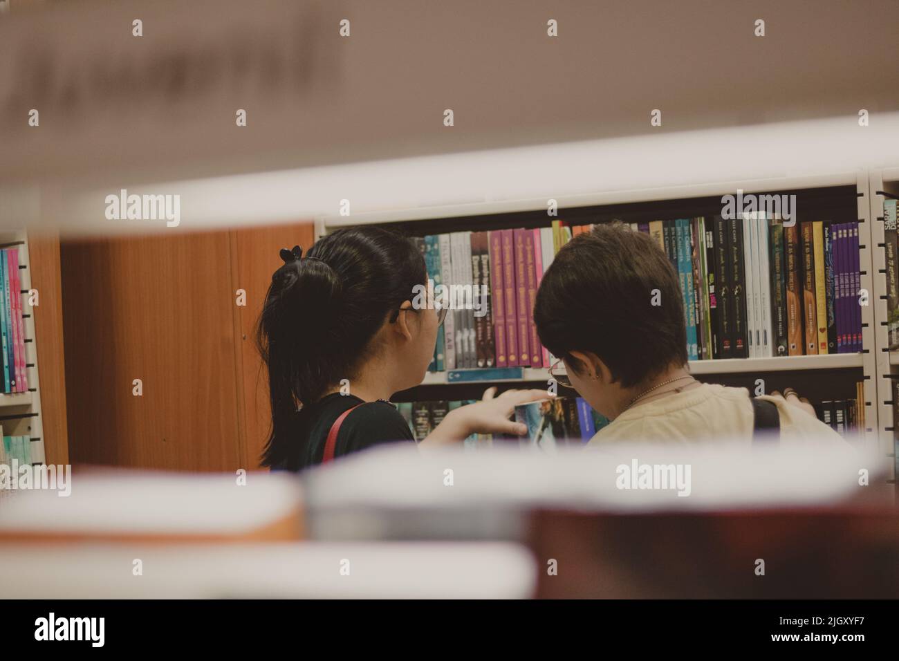 Zwei Mädchen, die in einer Buchhandlung in die Regale schauen Stockfoto