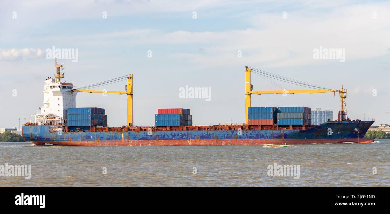 Das Containerschiff, das mit Containern beladen ist, fährt an einer Küste entlang Stockfoto