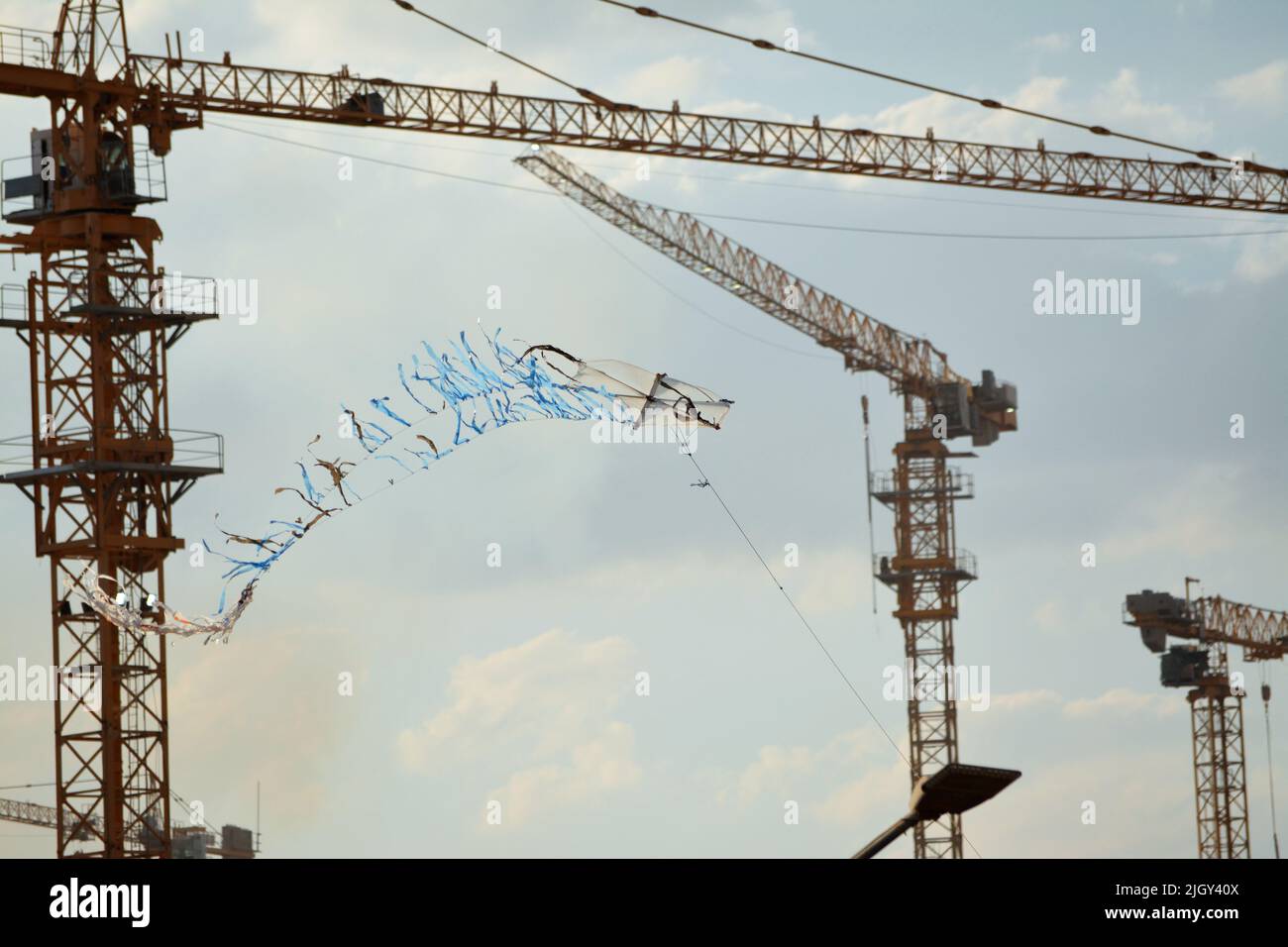 Fliegender Drachen aus Kunststoff und Korbholz mit einem Hintergrund einer Baustelle von Neubauten, Kränen und Hektar luxuriöser Immobilien resid Stockfoto