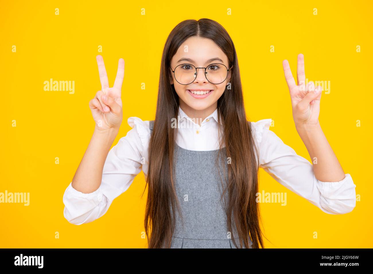 Teenager Kind Mädchen zeigt Finger Siegeszeichen. Nummer zwei, auf gelbem Hintergrund isoliertes V-Zeichen-Symbol. Stockfoto
