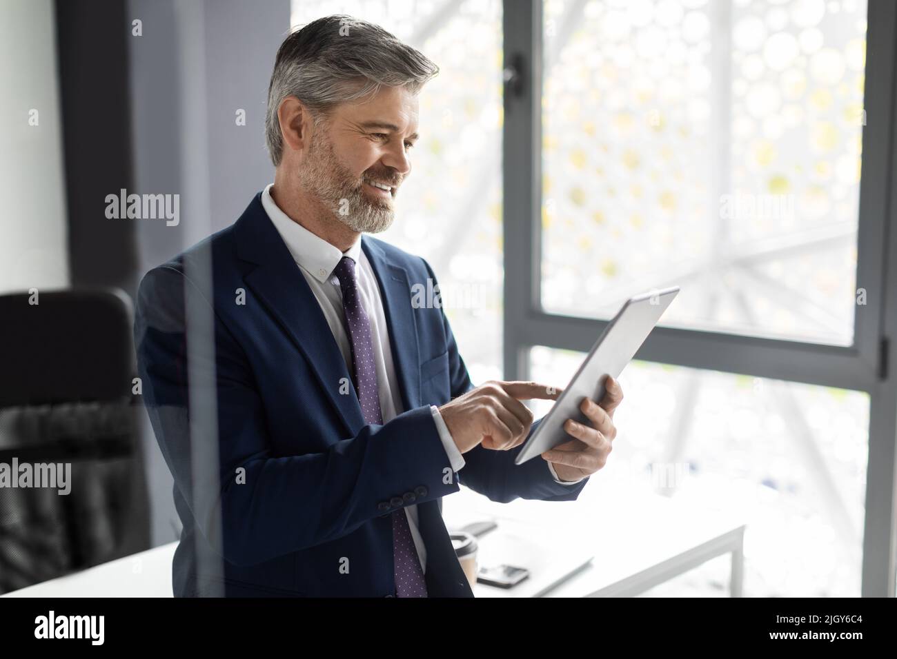 Erfolgreicher Reifer Geschäftsmann Mit Digitalem Tablet Am Arbeitsplatz Im Büro Stockfoto