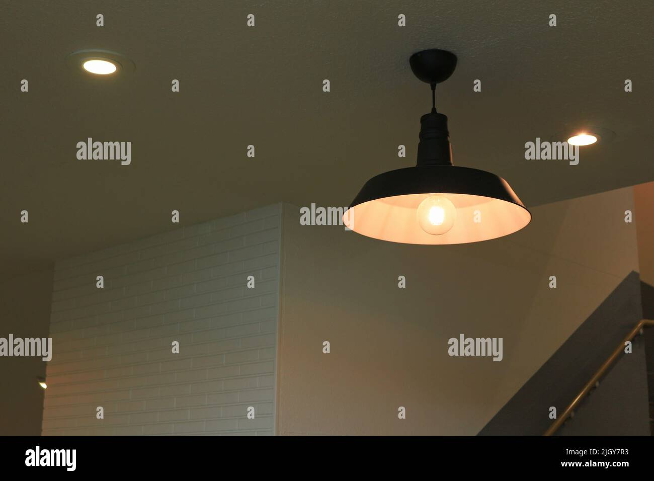 Die Beleuchtung eines Lampenschirms aus Eisen mit einem schlichten Design hing in einem schwach beleuchteten Raum Stockfoto