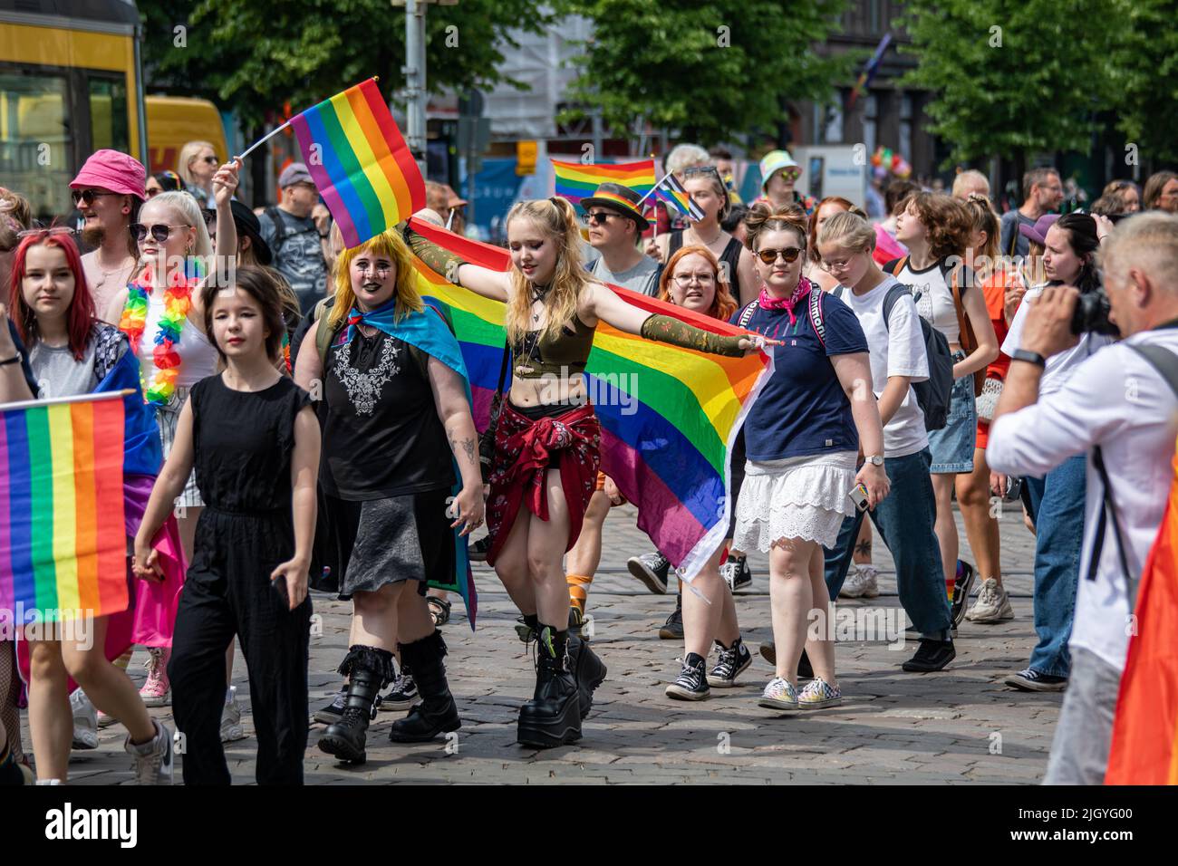 Junge Menschen mit Regenbogenfahnen oder Stolzflaggen bei der Helsinki Pride 2022 Parade in Mannerheimintie, Helsinki, Finnland Stockfoto