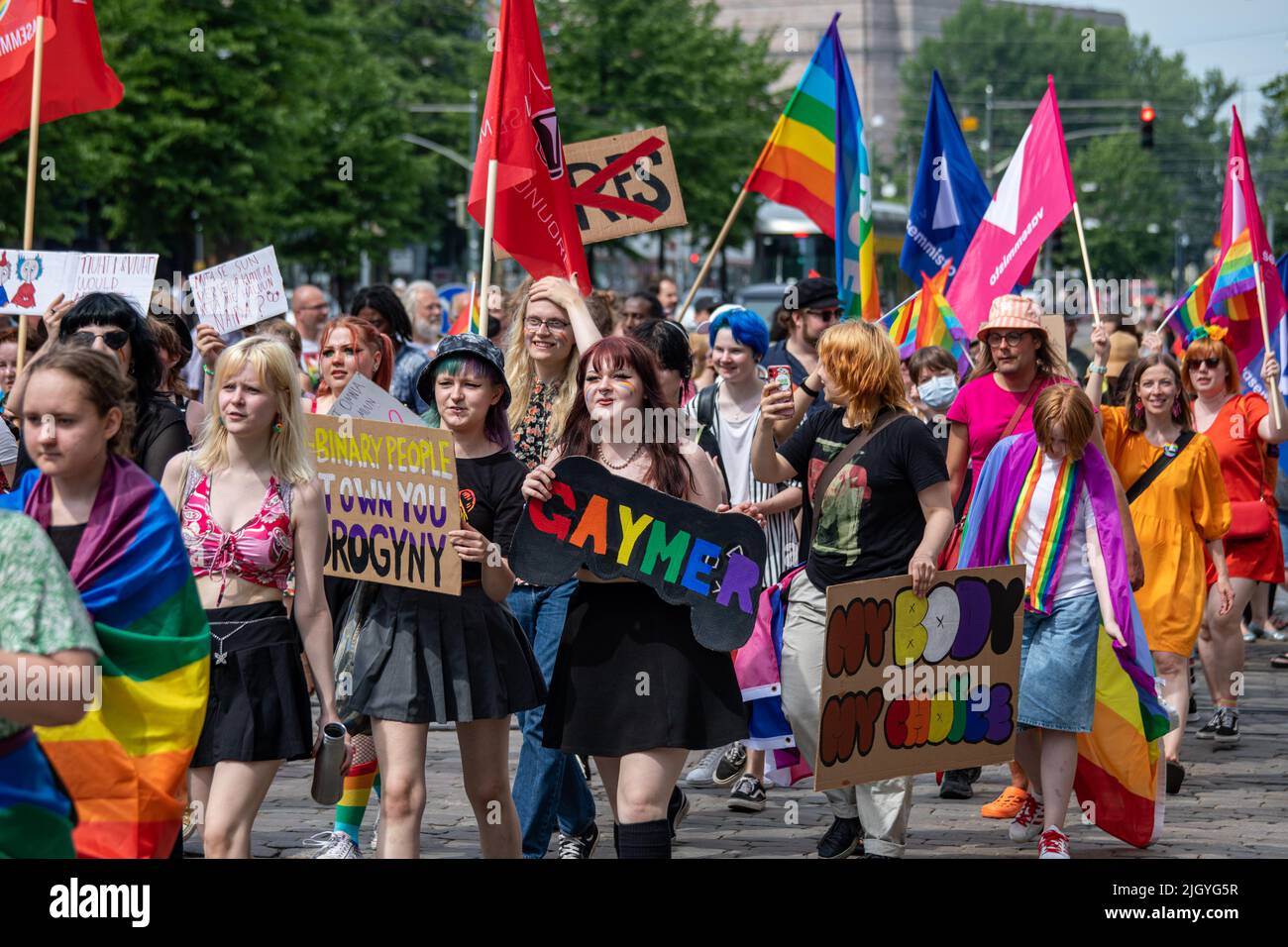 Junge Menschen marschieren mit Schildern und Fahnen bei der Helsinki Pride 2022 Parade in Mannerheimintie, Helsinki, Finnland Stockfoto