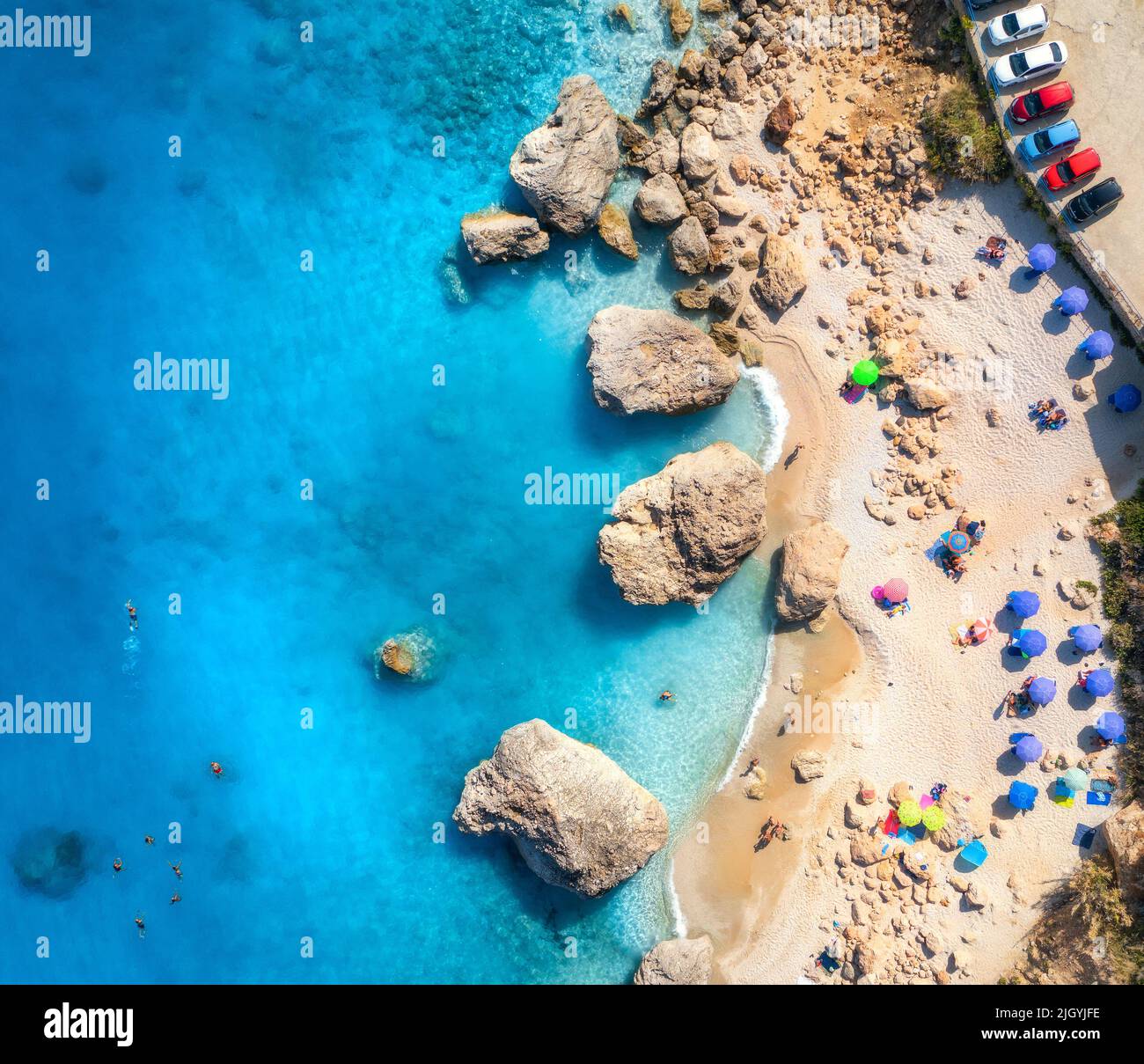 Luftaufnahme des blauen Meeres, Strand mit Sonnenschirmen, Felsen im Wasser Stockfoto