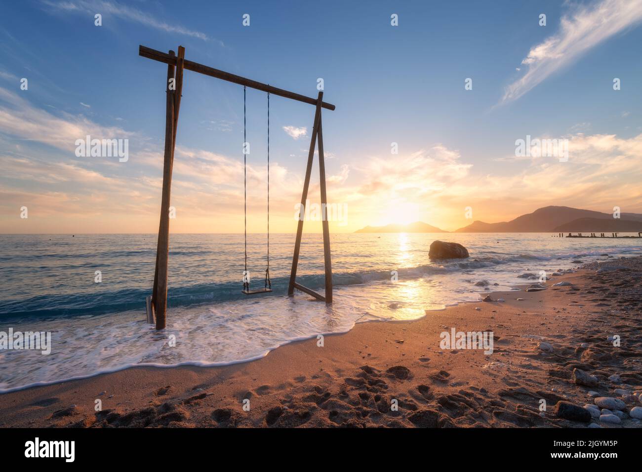 Holzschaukel im wunderschönen blauen Meer mit Wellen, Sandstrand Stockfoto