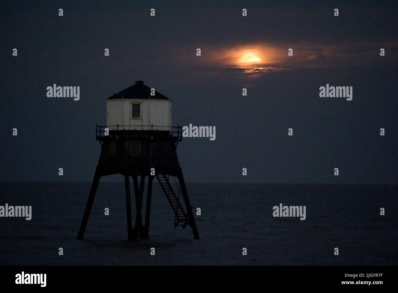 Essex, Großbritannien. 13.. Juli 2022. Dovercourt Essex UK 13.. Juli 22 der Super Buck Moon steigt hinter dem Dovercourt Lower Lighthouse in Essex auf. Der Super Buck Moon ist der zweite Supermond des Jahres und der erste Vollmond des Sommers 2022. Quelle: MARTIN DALTON/Alamy Live News Stockfoto