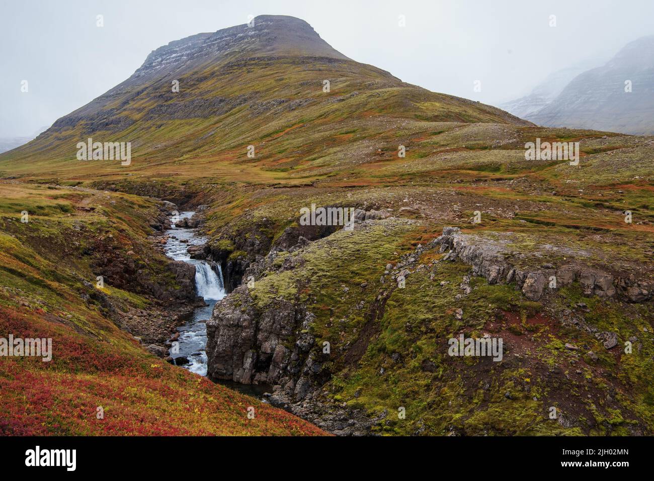 Ich glaube, dieser kleine Bach heißt Slenja. Der Wasserfall ist von der Route 953 direkt an der Grenze zwischen den Regionen Mjóafjarðarheiði und MJ zu sehen Stockfoto