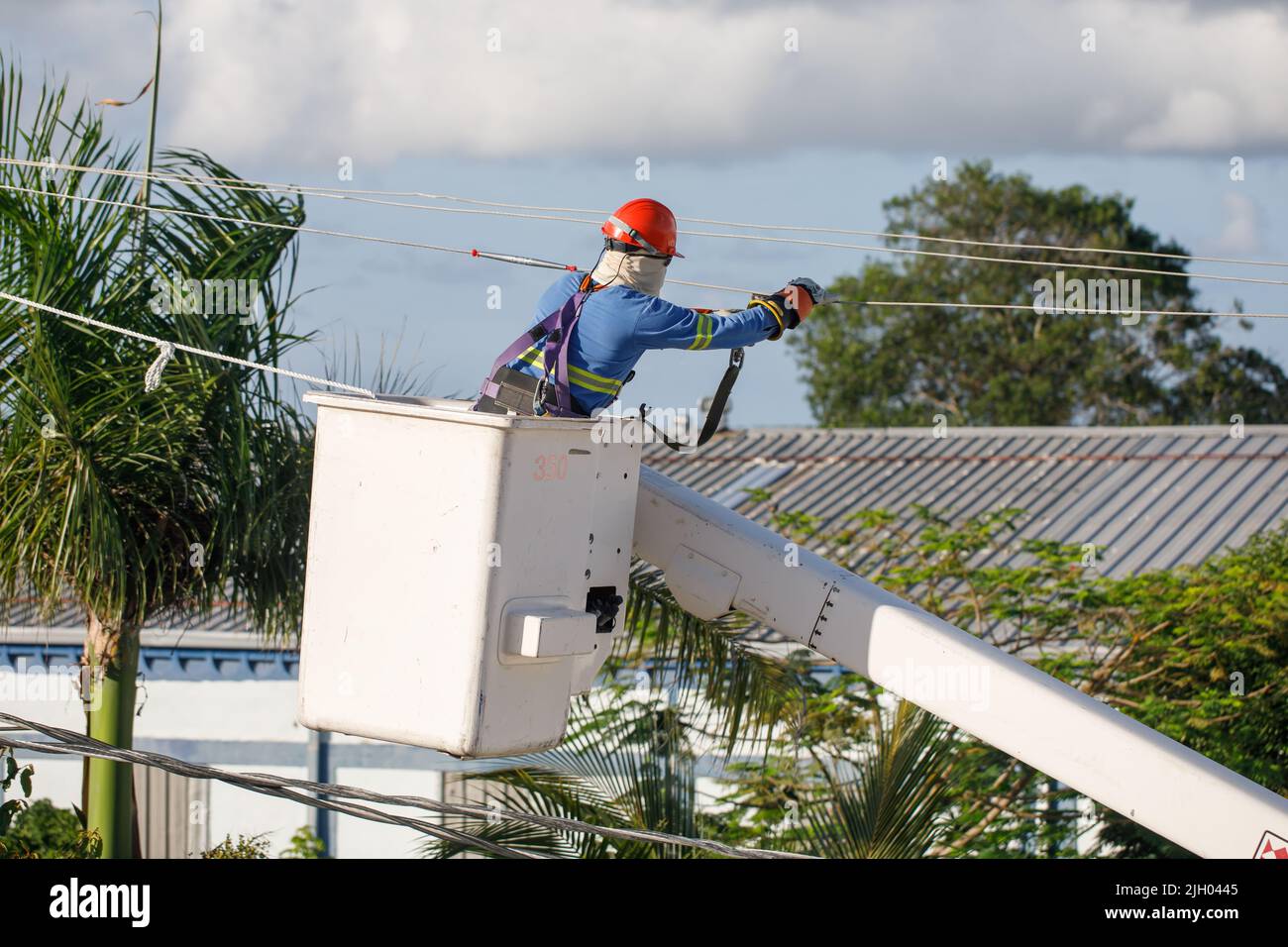 Ein Elektriker an einem Mast ist mit der Installation von elektrischen Drähten beschäftigt. Stockfoto